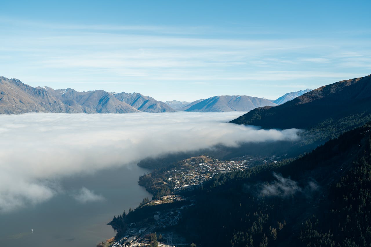 Stunning aerial landscape of Queenstown, New Zealand with mountains and misty clouds.